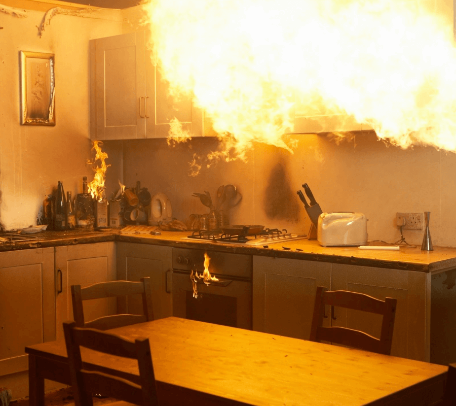 A kitchen with fire coming out of the ceiling.