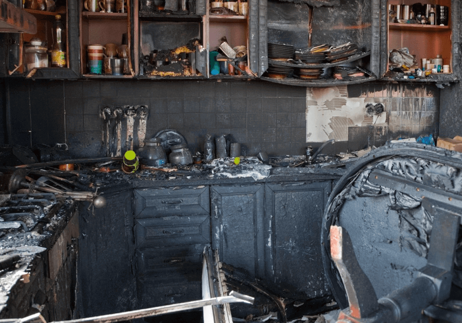 A kitchen with black cabinets and walls that are burned.